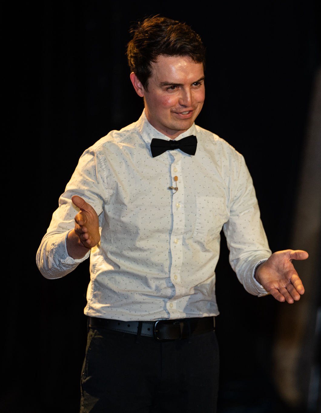 Ben Rush speaking on stage in a bow tie during a live performance.